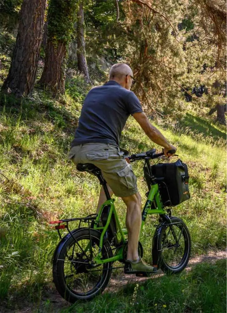 Radfahrer auf einem grünen E-Bike mit Korb auf einem Waldweg