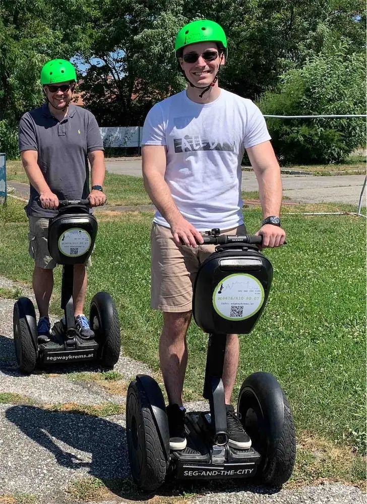 Zwei Fahrer mit grünen Helmen auf Segways am Übungsplatz