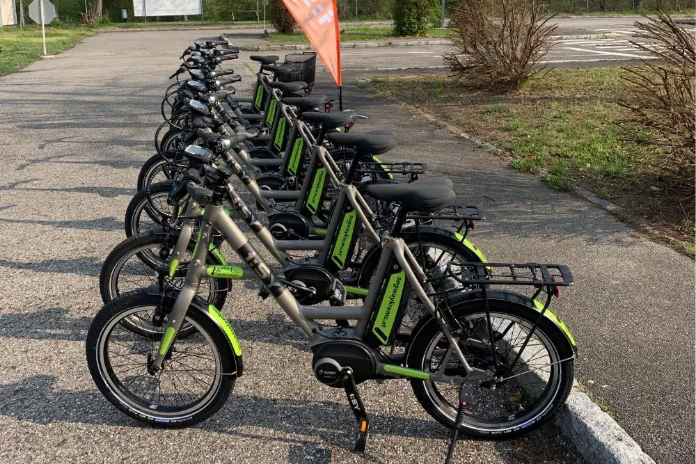 Eine Reihe grauer i:SY-E-Bikes mit grünen Akkus auf dem Übungsplatz