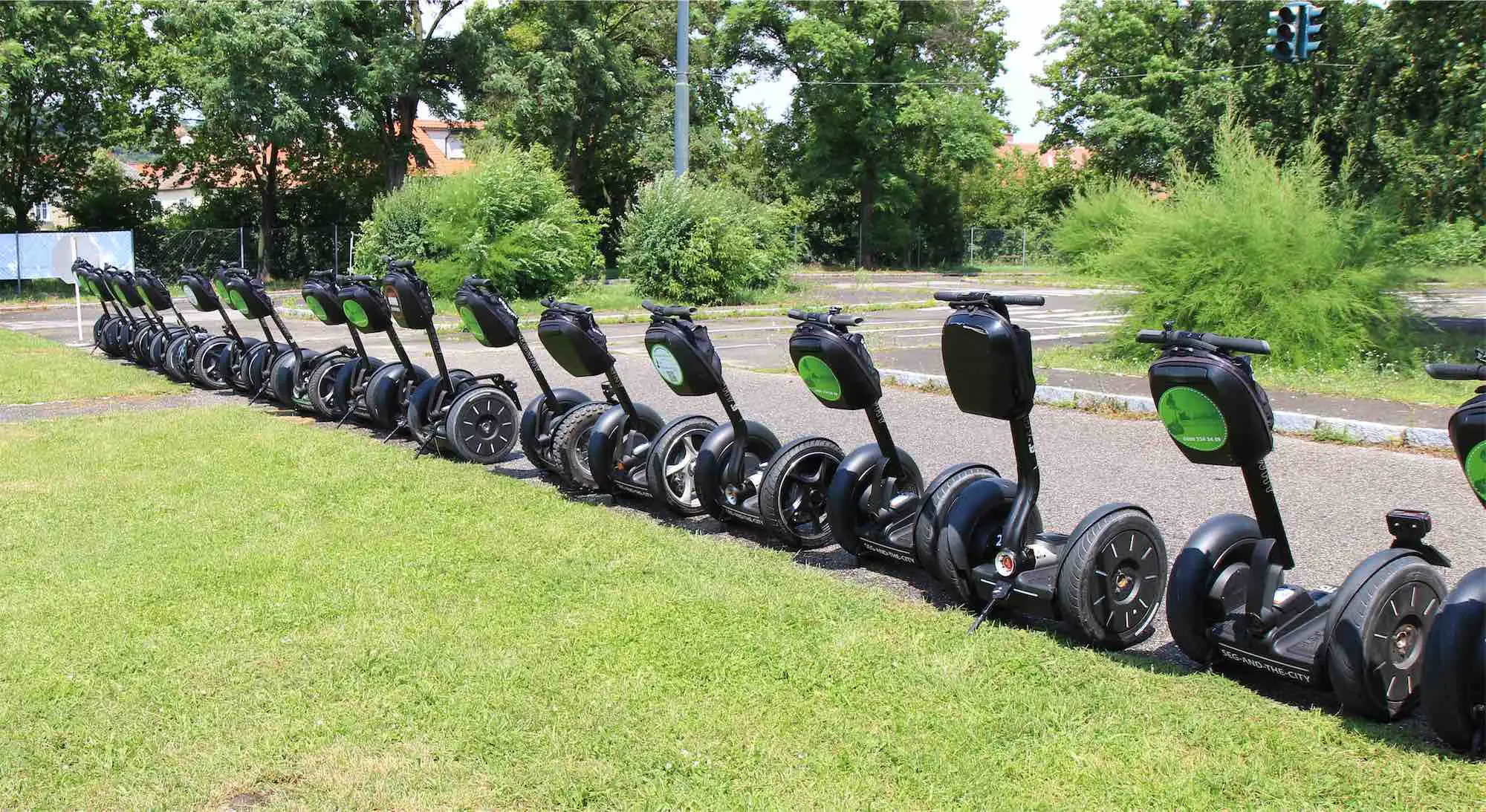 Segways mit grünen Taschen in einer langen Reihe am Rand des Übungsplatzes