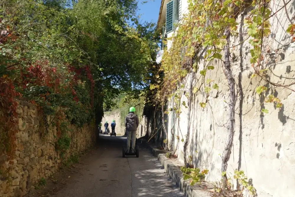 Segway-Fahrer in einer schmalen Gasse zwischen Mauern mit Weinranken