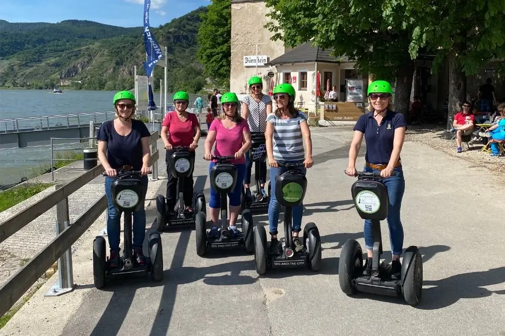 Gruppe auf Segways mit grünen Helmen an der Schiffsanlegestelle Dürnstein